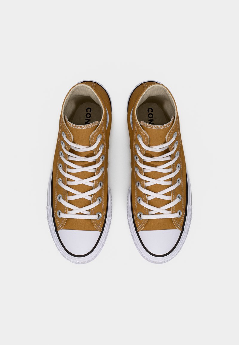 Sneakers alte in tela marrone con lacci bianchi, puntali in gomma nera e suola bianca, caratterizzate da un design semplice e classico.