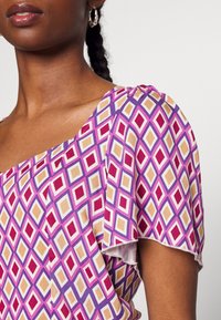 Maglietta a maniche corte con un motivo a diamante rosa, viola e oro. Tessuto morbido con una vestibilità comoda e scollatura rotonda.