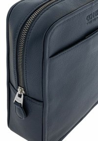 Granatowa skórzana torba z fakturowaną powierzchnią, z zamkiem błyskawicznym z metalu srebrnego oraz małą kieszonką z przodu. Gładkie krawędzie i minimalistyczny design.