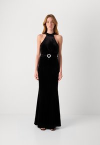 Juoda aksominė suknelė su halter iškirpte, prigludusia bodice ir išsiplėtusiu sijonu. Pabrėžia diržas su deimantais širdelės forma, pabrėžiantis liemeni.