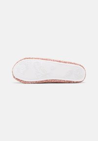 Chaussure florale rose à enfiler vue de la semelle avec une semelle extérieure blanche présentant des motifs floraux en relief et une indication de taille 20.