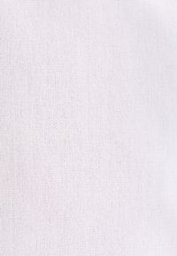 Hvidt tekstureret stof med et fint, jævnt strikkemønster, oplyst for at fremhæve materialets vævning og overfladedetaljer.