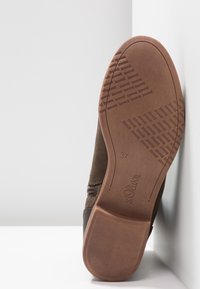 Botte en daim marron avec une semelle en caoutchouc dotée d'un motif de grip texturé. Taille 37 marquée sur la semelle, avec un détail de fermeture éclair latérale.