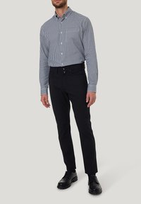 Kariertes kurzärmliges Hemd für Herren in Marineblau und Weiß, kombiniert mit schwarzer Slim-Fit-Hose und schwarzen Schnürschuhen.