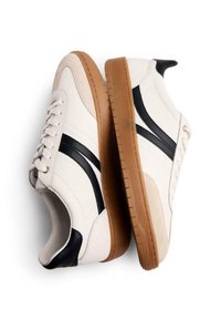 Sneakers bianchi in pelle con accenti neri e suola in gomma. Presentano una punta arrotondata, design con lacci e pannelli testurizzati.