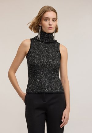 Svart ärmlös polotröja med texturerad, ribbad design och inslag av silvriga metalltrådar; åtsittande form, kombinerad med svarta byxor.