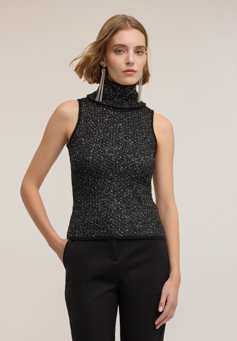 Svart ärmlös polotröja med texturerad, ribbad design och inslag av silvriga metalltrådar; åtsittande form, kombinerad med svarta byxor.