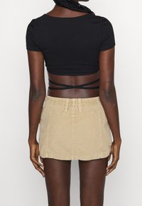 Top negro corto de mangas cortas, combinado con una falda de pana beige con cintura elástica y bolsillos traseros.