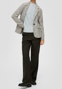 Texturierte, grau-weiße, gewebte Blazerjacke kombiniert mit einem hellblauen Pullover und dunklen, weiten Hosen. Schwarze flache Schuhe runden den Look ab.