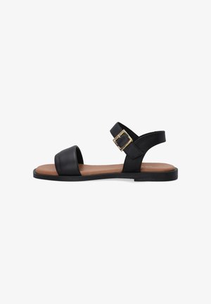 Black leather sandal with a wide toe strap and an adjustable ankle strap featuring a gold-tone buckle. Flat sole with a brown footbed.