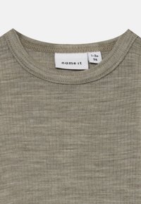 Khakigrünes, geripptes Kurzarmshirt mit rundem Halsausschnitt. Das Etikett zeigt die Größe 1-2 Jahre und die Marke "name it". Weicher, strukturiert Stoff.