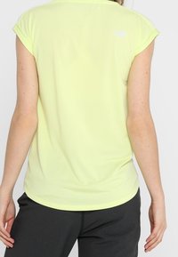 Korte mouw, lichtgele sportshirt gemaakt van gladde stof. Heeft een ronde halslijn en een klein logo op de bovenrug.