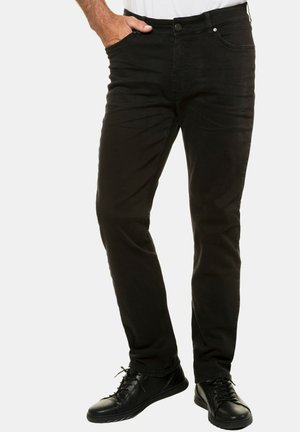 Sorte denimjeans med slim fit, der har et klassisk fem-lomme design og en knaplukning. Båret med sorte snørebåndssko.