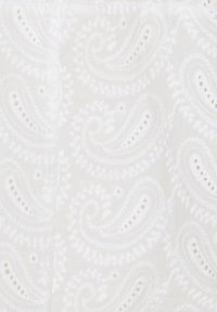 Tissu blanc avec un motif de broderie paisley, présentant une texture en relief et de petites découpes œillet tout au long.