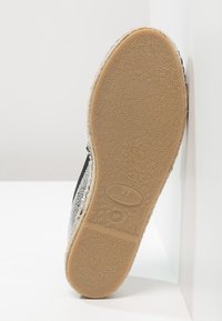 Chaussure noire et argent avec surface texturée et semelle en caoutchouc. Taille 37 marquée, fabriquée en Espagne. La semelle est de couleur beige avec un motif moucheté.