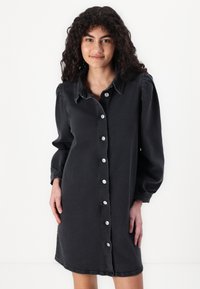 Rochie din denim neagră, cu guler, mâneci lungi tip balon și închidere cu nasturi în față. Prezintă nasturi argintii și are o croială lejeră.