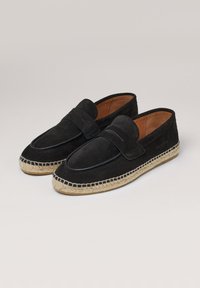 Mocasines de ante negro con suela de yute trenzada, presentan un detalle de costura y un diseño plano con un acabado suave.