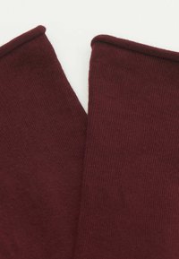 Bordeaux ribbet stof med en glat tekstur, der har et foldet kantdesign og to overlaprende sektioner, som viser en dyb farverigdom.