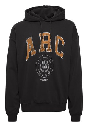Crna dukserica s istrošenim natpisom "ARC" u narančastoj boji, kružnim grafičkim dizajnom i rebrastim rukavima i rubom. Napravljena od mekanog materijala.