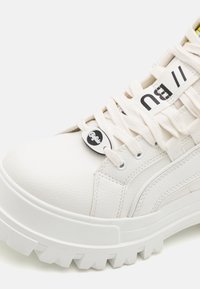 Hvide læder platform sneakers med rund tå, tekstureret overflade og tyk, tandet gummisål. Har kontrasterende snørebånd og logo-detaljer.