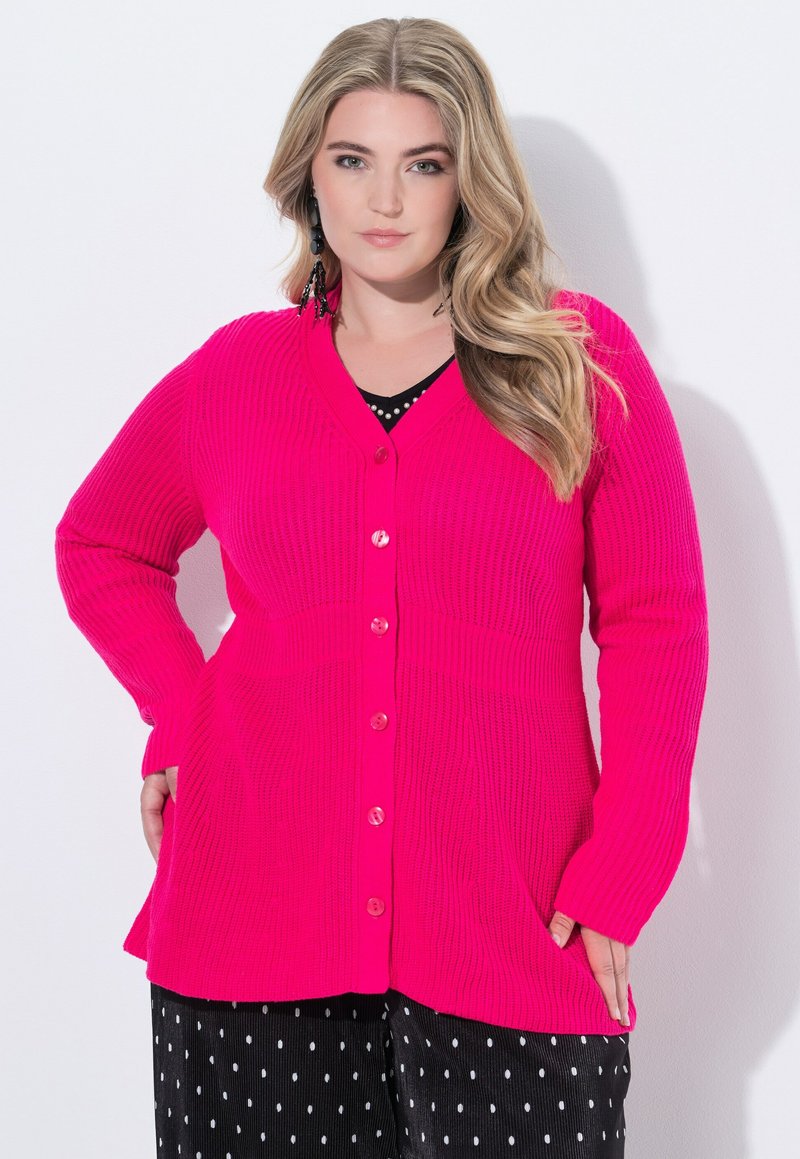 Sweter dzianinowy w intensywnym różowym kolorze z dekoltem w serek, długimi rękawami i guzikami z przodu. Posiada teksturowaną tkaninę oraz boczne kieszenie.
