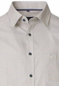 Witte blouse met een geometrisch patroon in blauw en beige. Voorzien van een klassieke kraag en contrasterende knopen. Gladde stoftextuur.