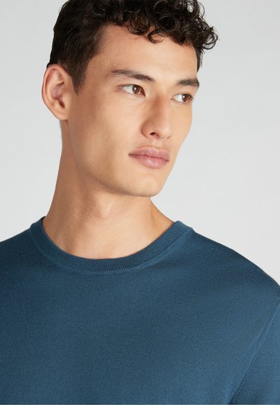 Maglione azzurro a collo rotondo con finitura strutturata. Presenta un design aderente e un tessuto morbido. Nessun motivo o accento visibile.