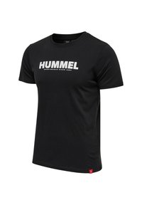 Svart t-shirt med kort ärm i bomull, prydd med ett stort vitt "HUMMEL"-logotyp på framsidan och en liten röd accenttag på fållen.