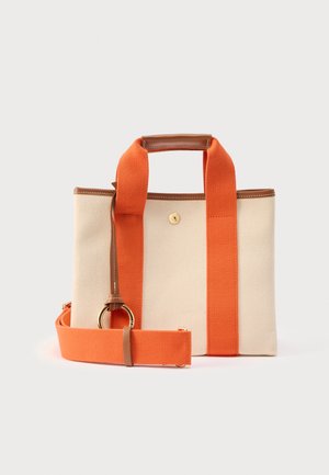 Beige canvas shopper met brede oranje stoffen hengsels, bruine leren biezen en een afneembare oranje schouderriem met een gouden ringgesp.