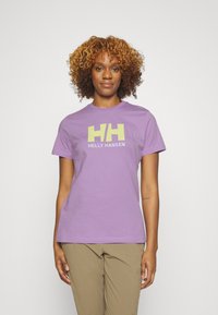 Camiseta de algodón púrpura con un logo de "Helly Hansen" en amarillo y blanco. Mangas cortas y un diseño clásico de cuello redondo.
