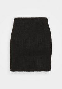 Černá sukně s přiléhavým střihem, textura látky se svislými žebry a pevný pas. Minimalistický design bez viditelného kování.