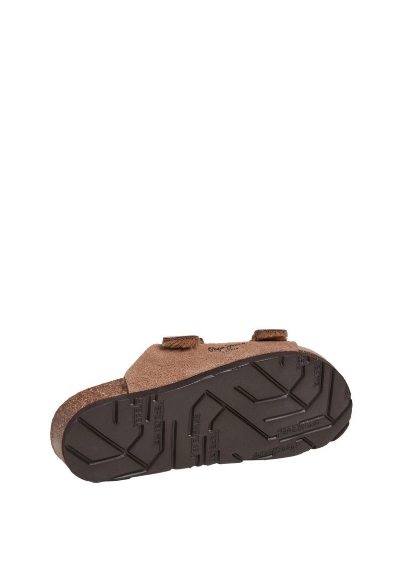 Braune Wildleder-Fußbekleidung mit verstellbaren Riemen und einer strukturierten schwarzen Gummisohle mit einem Zickzackmuster, entworfen für Komfort und Grip.