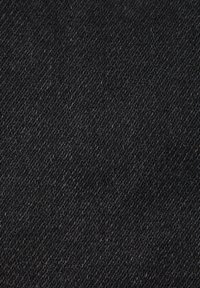 Zbliżenie czarnej tkaniny jeansowej, ukazujące szczegółową teksturę diagonalnego splotu.