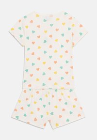 Zweiteiliges Pyjama-Set aus Baumwolle mit einem kurzärmeligen Oberteil und Shorts. Weißer Hintergrund mit bunten Herzmustern in Pink, Gelb und Türkis.