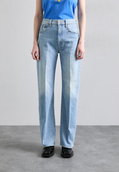 Light blue high-waisted jeans with a loose fit, featuring subtle fading, five pockets, and a button closure. Paired with black shoes.