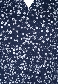 Tessuto blu navy con motivo floreale in bianco; presenta piccoli fiori e pallini, con un design a V. Texture liscia.