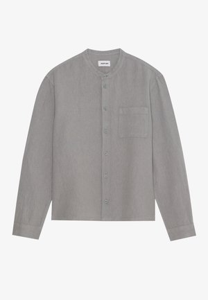 Dlouhý rukáv, košile na knoflíky ze světle šedé látky. Má kulatý výstřih, jednu náprsní kapsu a měkkou strukturu.