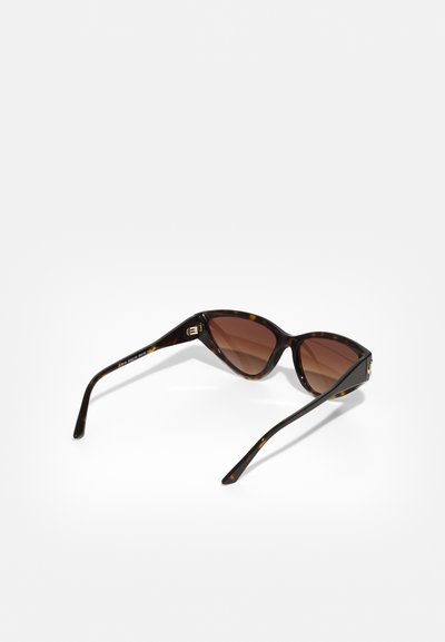 Lunettes de soleil en écaille de tortue marron avec un design œil de chat, verres dégradés marron, branches fines et détails en métal doré.