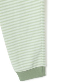 Pantalones a rayas verdes claros hechos de una tela suave. Cuentan con un puño acanalado verde en el tobillo, que mejora la comodidad y el ajuste.