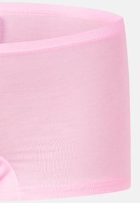 Ljust rosa sömlösa stretchunderkläder med en slät midjeband och platt sydda benöppningar på en vit bakgrund.