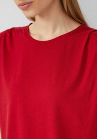 Rode katoenen T-shirt met een ronde hals, voorzien van korte mouwen en een soepele structuur. Eenvoudig ontwerp zonder zichtbare patronen of accenten.