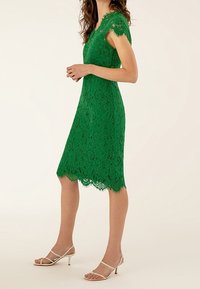 Robe en dentelle verte avec des manches courtes, corsage ajusté et ourlet festonné. Portez-la avec des talons nus à lanières. Motif floral texturé sur l'ensemble.