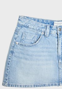 Ljusblå denim mini kjol med hög midja, med en främre ficka, metal knappstängning och subtilt sliten textur.