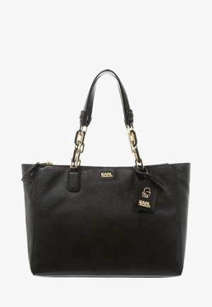 Sac fourre-tout en cuir noir avec chaîne dorée et poignées en cuir, arborant le logo Karl Lagerfeld et une étiquette suspendue avec la silhouette du logo.