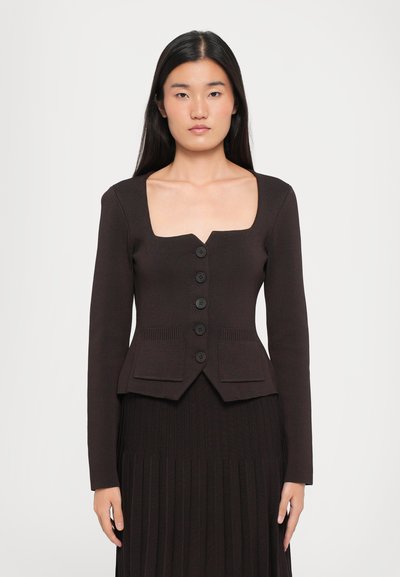 Brauner gerippter Langarm-Cropped-Cardigan mit quadratischem Ausschnitt, sechs schwarzen Knöpfen und zwei vorderen Taschen. Glatte Textur im gesamten Design.