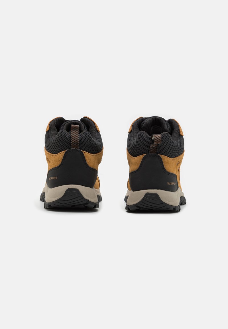 Chaussures de randonnée imperméables marron et noires avec un dessus texturé, un col rembourré et une semelle robuste, conçues pour les activités de plein air.