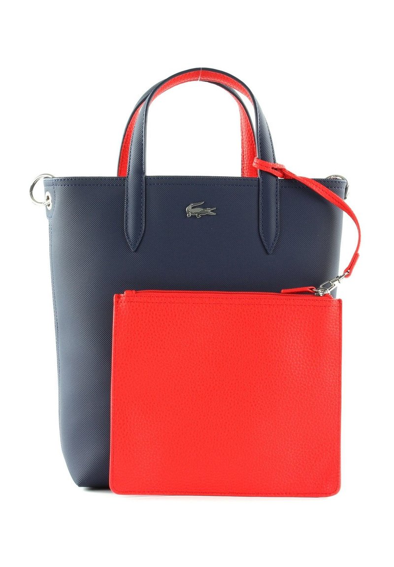 Sac fourre-tout bleu marine avec une finition texturée, arborant des poignées rouges et une pochette cosmétique rouge amovible. Accent logo argent sur le devant.
