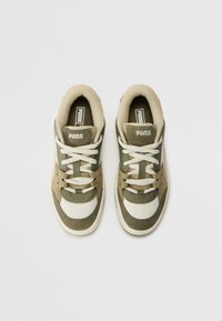 Puma sportcipő zöld, bézs és törtfehér dizájnban. Textil és velúr anyagokkal készült, kerek orrú, fehér fűzőkkel, és logóval a nyelvén.