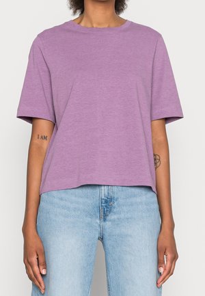 Lila T-Shirt mit kurzen Ärmeln und Rundhalsausschnitt, mit weicher Textur und entspannter Passform. Kombiniert mit hellblauen Denim-Jeans.