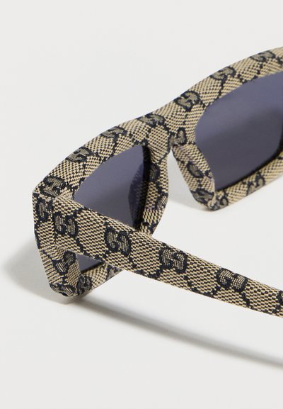 Ορθογώνια γυαλιά ηλίου με μπεζ και μαύρο ύφασμα στο πλαίσιο, διακοσμημένα με διαπλεκόμενο σχέδιο "GG" και σκουρόχρωμους φακούς.